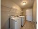 Laundry room with tile floor, washer, dryer, wire rack shelf, and door at 110 Evergreen Dr, Auburndale, FL 33823