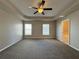 Main bedroom with tray ceiling, ceiling fan, carpet flooring and ensuite bathroom access at 110 Evergreen Dr, Auburndale, FL 33823