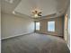 Large main bedroom with tray ceiling, ceiling fan, carpet flooring and two windows at 110 Evergreen Dr, Auburndale, FL 33823