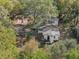 Aerial view of a home surrounded by mature trees, a covered patio, and a long driveway at 1208 Bonaire Dr, Leesburg, FL 34748