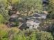 Aerial view of a home surrounded by mature trees, a covered patio, and a long driveway at 1208 Bonaire Dr, Leesburg, FL 34748