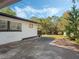 A view of the back of the house with concrete and grass, surrounded by trees at 1208 Bonaire Dr, Leesburg, FL 34748