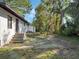 The backyard features trees, grass, and a glimpse of the house's back entrance at 1208 Bonaire Dr, Leesburg, FL 34748