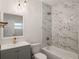 Bathroom featuring marble-style tiled shower, gray vanity, and contemporary gold fixtures at 1208 Bonaire Dr, Leesburg, FL 34748