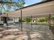 An outdoor carport with a concrete floor and pole supports with a glimpse of the yard at 1208 Bonaire Dr, Leesburg, FL 34748
