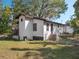 A view of the house's exterior, featuring a concrete base, dark trim, and a grassy lawn at 1208 Bonaire Dr, Leesburg, FL 34748