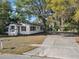 Inviting single-story home featuring a spacious driveway, mature trees, and a covered carport at 1208 Bonaire Dr, Leesburg, FL 34748