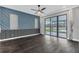 Spacious living room with dark wood floors, custom blue paneled wall, and access to the outdoor pool and patio at 12323 Sweet Hill Rd, Polk City, FL 33868