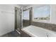 Relaxing bathroom with a soaking tub, glass-enclosed shower, and window at 15580 Blackbead St, Winter Garden, FL 34787