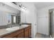 Bathroom featuring double sinks with a large mirror and tiled shower with glass doors at 15580 Blackbead St, Winter Garden, FL 34787