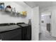 Well-lit laundry room with black washer and dryer and overhead storage shelving at 15580 Blackbead St, Winter Garden, FL 34787