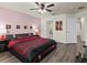 Bedroom featuring hardwood floors, a ceiling fan, and a king-size bed with red accents at 161 Orange Cosmos Blvd, Davenport, FL 33837