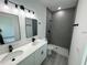 Modern bathroom features a double vanity, gray-tiled shower, and black hardware at 16947 Sw 22Nd Terrace Rd, Ocala, FL 34473