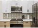 Close up of a kitchen with stainless steel microwave and oven, patterned backsplash, and a modern coffee maker at 1968 Compass Flower Way, Ocoee, FL 34761