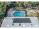 Aerial shot featuring screened-in pool, solar panels, landscaped backyard, and outdoor fire pit seating area at 204 Smokerise Blvd, Longwood, FL 32779