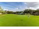 Scenic golf course view with lush green fairways, mature trees, and a clubhouse in the background under a blue sky at 229 Troon Cir, Davenport, FL 33897
