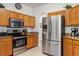 Modern kitchen with stainless steel appliances, granite countertops, and light wood cabinets at 229 Troon Cir, Davenport, FL 33897