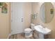 A simple half-bath includes a toilet and pedestal sink with a round mirror and neutral walls at 2327 Distant Sun Trl, Kissimmee, FL 34747