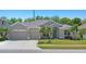 Charming single-story home featuring a three-car garage and neatly manicured front yard with tropical landscaping at 2501 Hinsdale Dr, Kissimmee, FL 34741