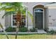 Inviting home entrance featuring a decorative front door, lush landscaping, and a well-manicured lawn at 2501 Hinsdale Dr, Kissimmee, FL 34741