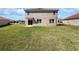 Large backyard featuring green grass, sliding glass doors to patio, and a view of the home's back exterior at 3056 Sangria St, Kissimmee, FL 34744