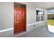 A close up of the front door, which is red, with a window next to it showing the front lawn at 3056 Sangria St, Kissimmee, FL 34744