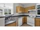 Functional kitchen features a double sink, oak cabinetry and white appliances at 3398 Greenwich Village Blvd # 104, Orlando, FL 32835