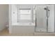 Bright bathroom featuring a soaking tub, glass shower, and a large window at 3747 Moon Dancer Pl, St Cloud, FL 34772