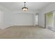 Living room featuring neutral carpet, modern light fixture, archways, and sliding glass door at 3747 Moon Dancer Pl, St Cloud, FL 34772