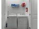 Bright laundry room featuring a white washer and dryer, storage shelf, and fire extinguisher at 418 Marcello Blvd, Kissimmee, FL 34746