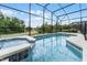 Relax in the luxurious, uniquely shaped pool and spillover spa with elegant tile work, enclosed within a screened-in lanai for comfort at 418 Marcello Blvd, Kissimmee, FL 34746