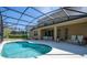 Backyard pool with screened enclosure, with view of backyard seating and exterior of home at 4561 Cabello Loop, Kissimmee, FL 34746