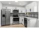 Modern kitchen featuring stainless steel appliances, white cabinets, and stylish backsplash at 5603 Marie Ct, Orlando, FL 32818