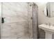 Updated bathroom featuring a shower with marble-look tile and a pedestal sink with modern fixtures at 6013 Thames Way, Orlando, FL 32807