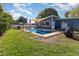 Relaxing backyard with in-ground pool, sunshade sail, grilling area, and ample green space at 6013 Thames Way, Orlando, FL 32807