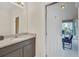 Well-lit bathroom with a granite countertop vanity and an open doorway to a sunroom at 6049 Broad Oak Dr, Davenport, FL 33837