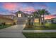 Beautiful two-story home with tropical landscaping, gray exterior, and a two-car garage, set against a colorful sky at 6049 Broad Oak Dr, Davenport, FL 33837