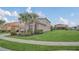 Charming two-story home with a lush green lawn, tropical trees, and a well-kept exterior at 6049 Broad Oak Dr, Davenport, FL 33837