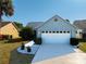 Charming single-story home featuring a two-car garage, flower garden, and well-manicured lawn at 704 Sky Tree Ct, New Smyrna Beach, FL 32168