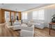 Elegant living room with modern furniture, wood floors, and large windows with sheer white curtains at 8010 Soldierwood St, Winter Garden, FL 34787