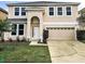 Two-story home showcasing the front yard with lush green lawn, complemented by landscaping and a two-car garage at 10071 Cypress Knee Cir, Orlando, FL 32825