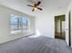 Sunlit bedroom featuring soft gray carpet, a ceiling fan, and a large window, providing a cozy and bright space at 1049 Winding Water Way, Clermont, FL 34714