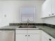 A kitchen featuring stainless steel sink and faucet with green countertops and white cabinetry at 1049 Winding Water Way, Clermont, FL 34714