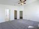 A primary bedroom featuring carpeted floors, ceiling fan, and access to the primary bathroom at 1049 Winding Water Way, Clermont, FL 34714