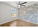 Bedroom with wood floors, a decorative accent wall, and a ceiling fan, offering a modern aesthetic at 122 Capri Dr, Davenport, FL 33897