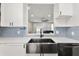 Modern kitchen featuring a stainless steel sink, updated appliances, and blue honeycomb tile backsplash at 122 Capri Dr, Davenport, FL 33897