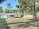 View of the backyard showing the home with a screened porch and mature trees at 145 W Fern Dr, Orange City, FL 32763