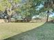 Large grassy backyard is surrounded by a wooden fence and mature shade trees at 145 W Fern Dr, Orange City, FL 32763