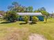 Single-story home with a metal roof, a charming front walkway, a lush green lawn and mature trees at 15765 Sunflower Trl, Orlando, FL 32828