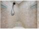 Detailed view of the walk-in shower with travertine tile, glass shelves, and an updated shower head at 15765 Sunflower Trl, Orlando, FL 32828